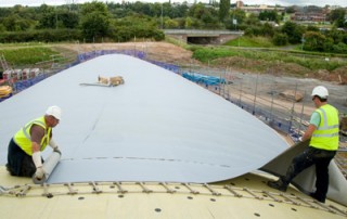 Single Ply Roofing Membrane being Laid over a curved roof